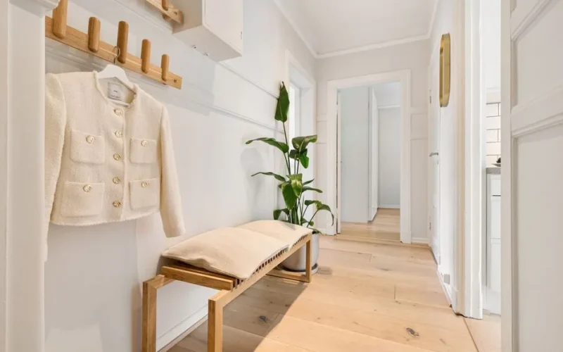 Bright minimalist hallway featuring wooden furniture and a stylish coat rack.