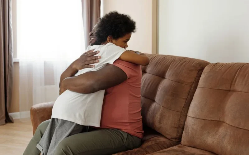 Father and son sharing a warm embrace on the sofa, expressing love and family togetherness.