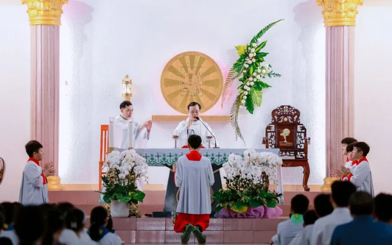 A priest conducting a Catholic mass with altar servers in a beautifully decorated church.