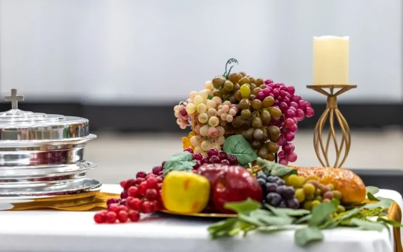 Beautiful arrangement of communion elements with fruits and candle on table.