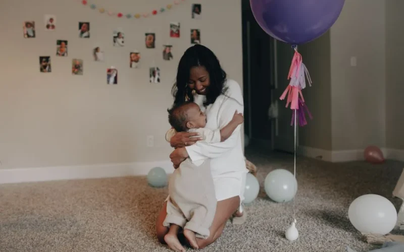A tender moment of a mother hugging her child during a birthday celebration indoors.