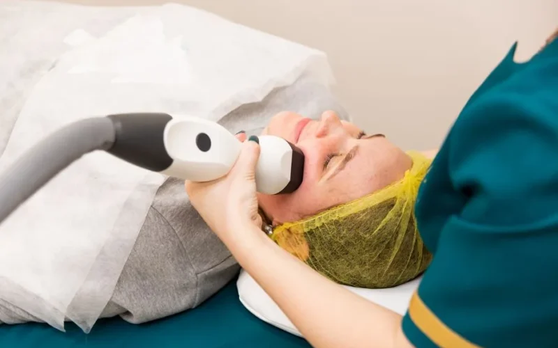 A woman receiving professional facial treatment at a clinic, highlighting beauty and technology.