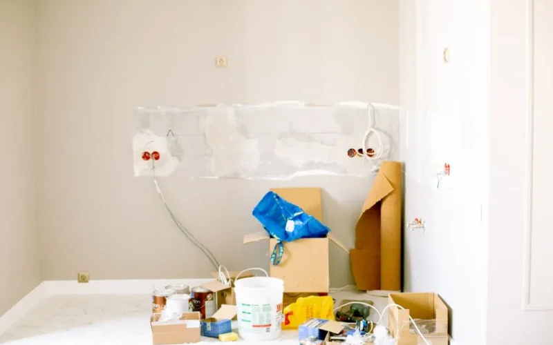 A room undergoing renovation with tools, supplies, wiring, and paint cans scattered around.