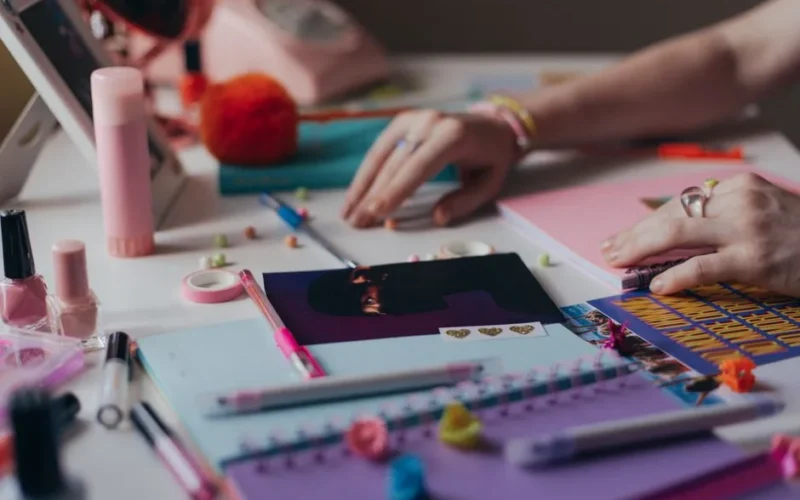 A close-up of a vibrant and colorful workspace featuring stationery and a woman's hands organizing supplies.