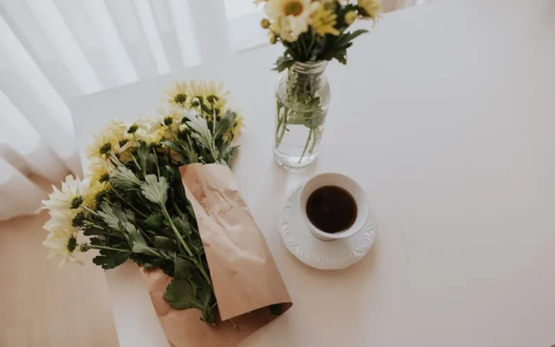 A bright morning scene with coffee and daisies on a white table, creating a fresh vibe.