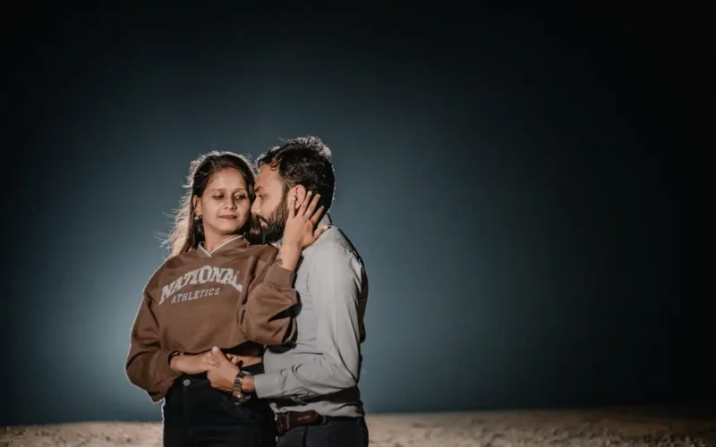 A couple shares a tender moment under a night sky, showcasing love and connection.