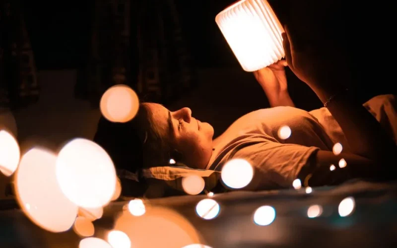A woman enjoying a peaceful bedtime reading with warm lighting and bokeh effect.