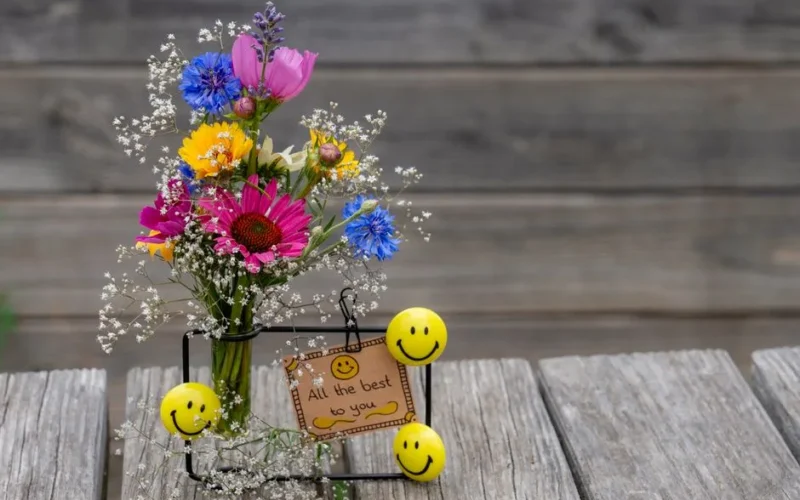 Vibrant bouquet with flowers and smiley decoration on rustic wood background.