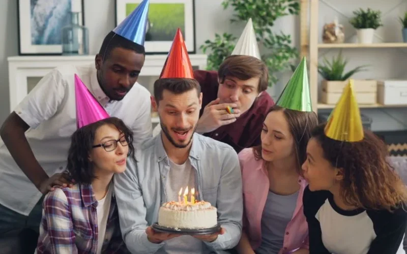 Group of friends celebrating with a birthday cake indoors.