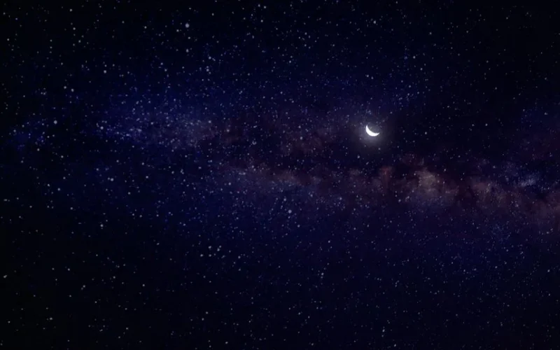 A breathtaking view of the starry night sky featuring the Milky Way and a waning crescent moon.