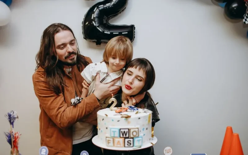 A joyful family celebrates their child's second birthday with a themed cake.