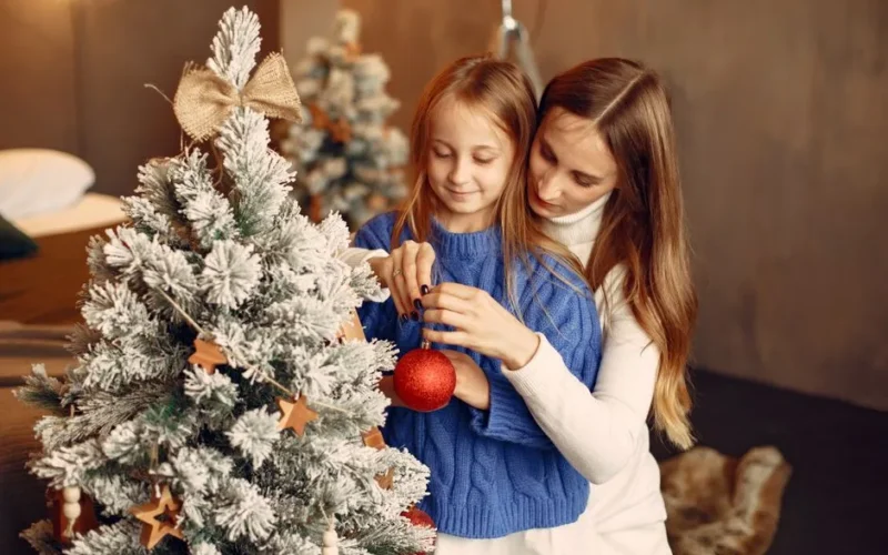 A warm family moment with mother and daughter decorating a Christmas tree together.