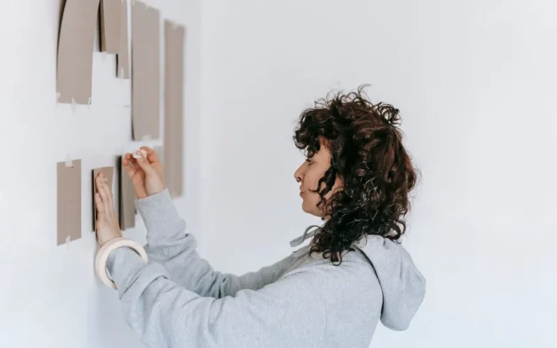 A woman decorates her apartment with cardboard pieces, focusing on home improvement.