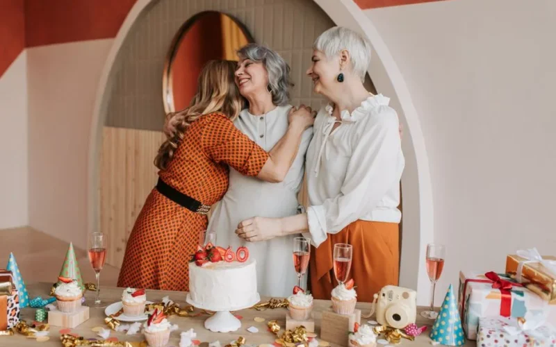 Three senior women celebrating a birthday, enjoying good company and cake indoors.