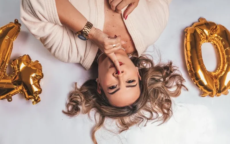 Elegant woman celebrating her 40th birthday with golden balloons in a stylish setting.