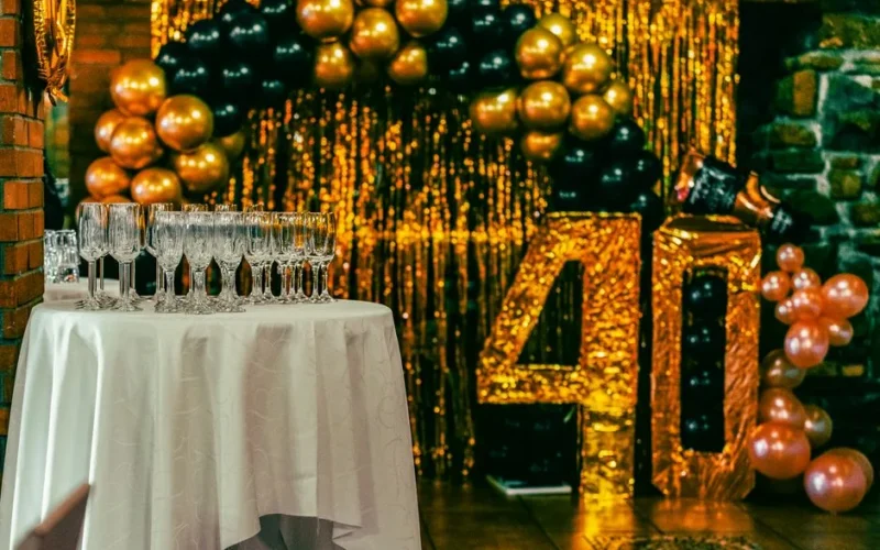 Chic 40th birthday party setting with champagne flutes, balloons, and gold glitter backdrop.