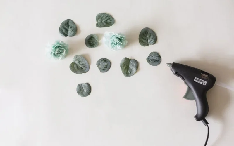 Arrangement of artificial flowers and leaves with a glue gun, perfect for DIY crafts.