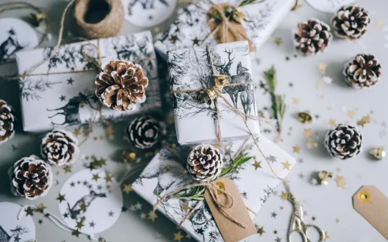 Beautifully wrapped Christmas gifts with pine cones and star confetti, capturing a festive holiday vibe.