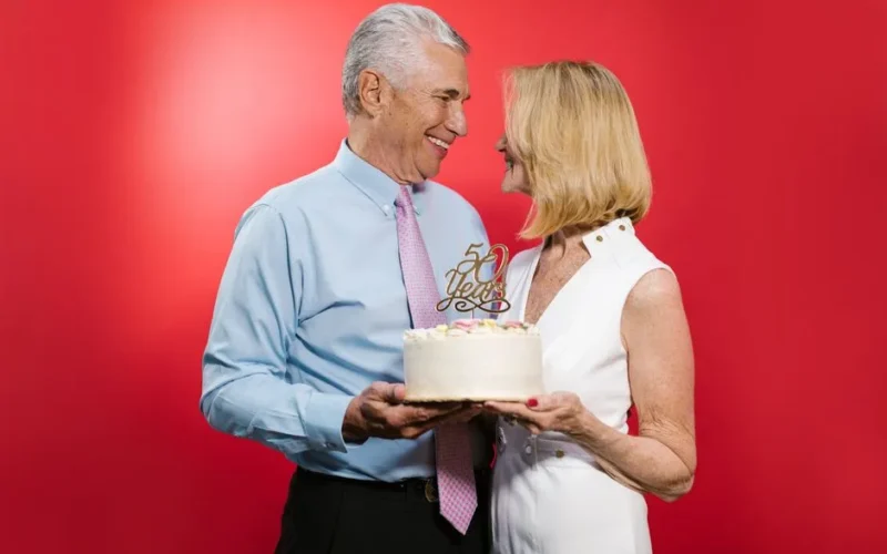 Happy senior couple celebrating their 50th anniversary with cake in a studio setting.