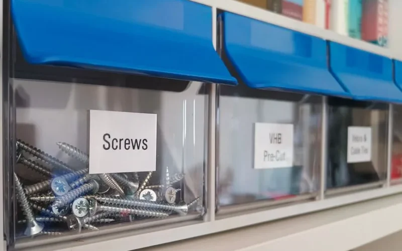 Clear plastic storage bins with screws for organized home workshop setups.