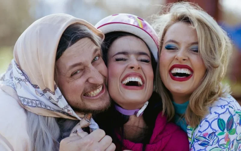 Three friends laughing joyfully outdoors, capturing happy moments together.