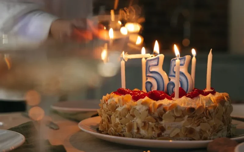 Close-up of a festive cake with lit candles marking a special 55th birthday celebration.