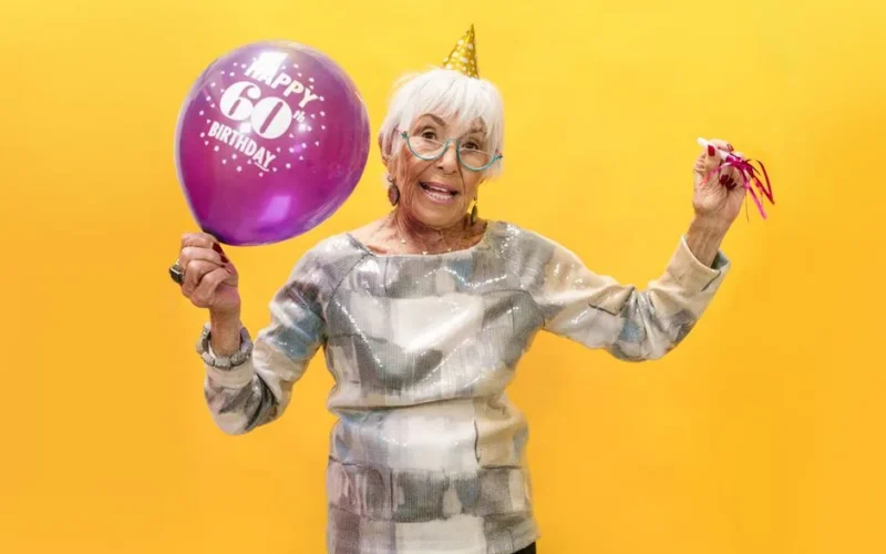 Vibrant photo of a happy senior woman celebrating her 60th birthday with a balloon.