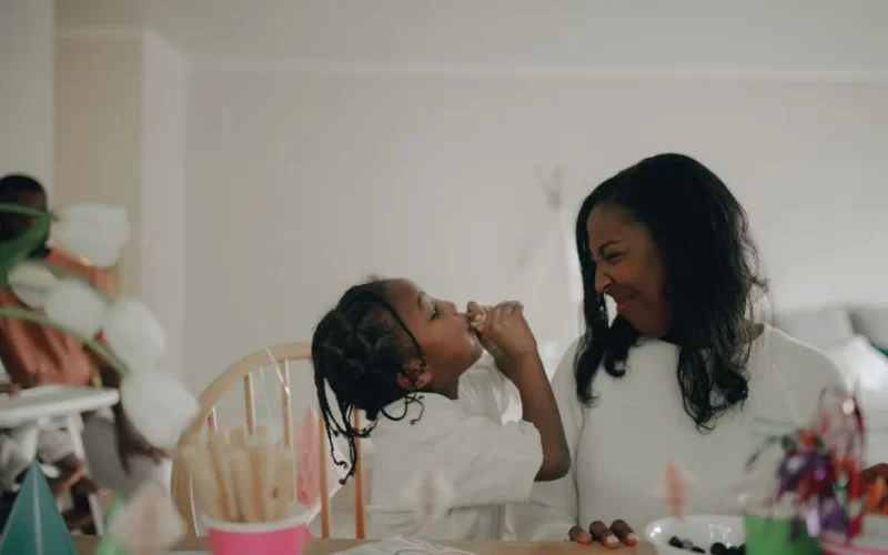 A mother and daughter share a joyful moment during a birthday celebration with festive decorations.