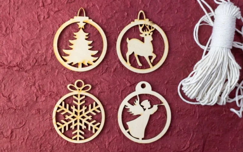 Flat lay of wooden Christmas ornaments featuring tree, reindeer, angel, and snowflake on a textured red background.