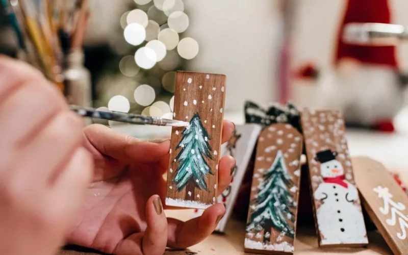 Hand painting wooden Christmas decorations with festive themes. Perfect for holiday crafting.