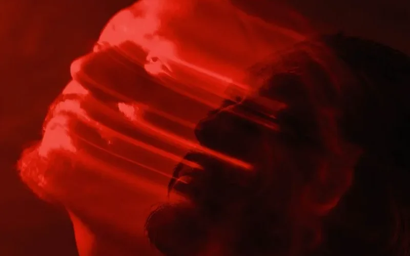 Artistic double exposure of a man with a red blurred motion effect, conveying emotion.