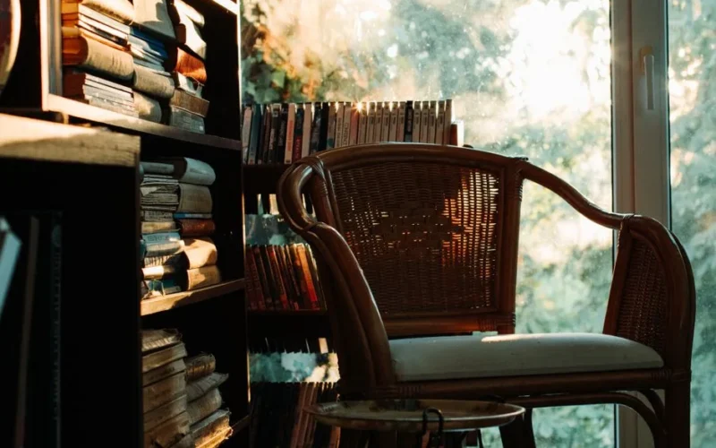 A warm, inviting reading nook with a wicker chair by a bookshelf, bathed in soft light.