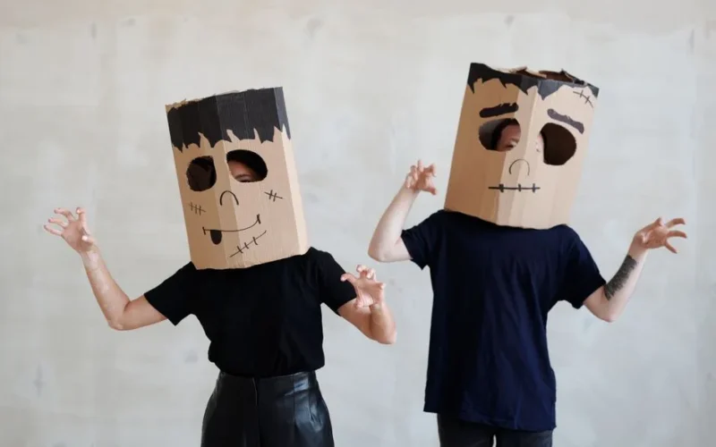 Two people wearing fun DIY cardboard Halloween costumes with spooky designs.