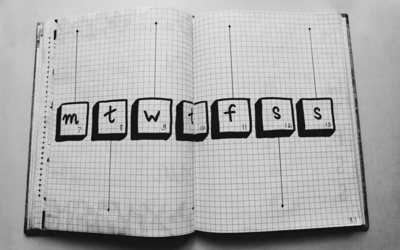Open grid notebook with days of the week drawn inside boxes, perfect for planners.