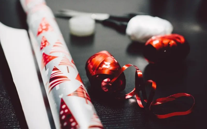 Colorful gift wrapping paper and red ribbon set the tone for holiday gift preparation.