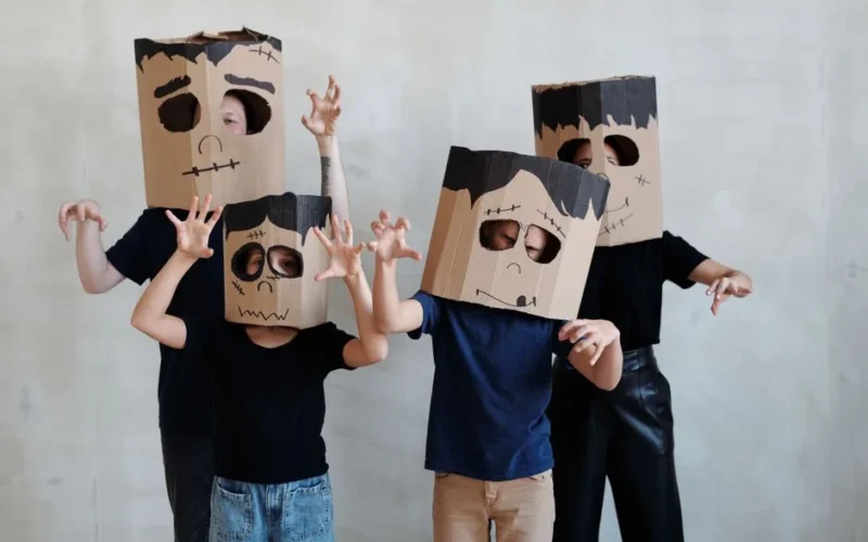 Group of children in DIY cardboard ghost costumes posing playfully for Halloween.