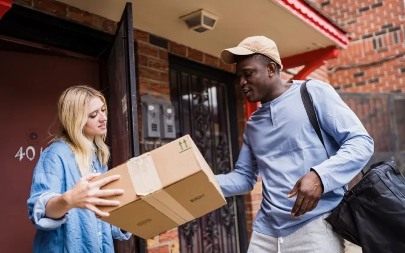 A delivery man handing a package to a woman at her doorstep, emphasizing delivery services.