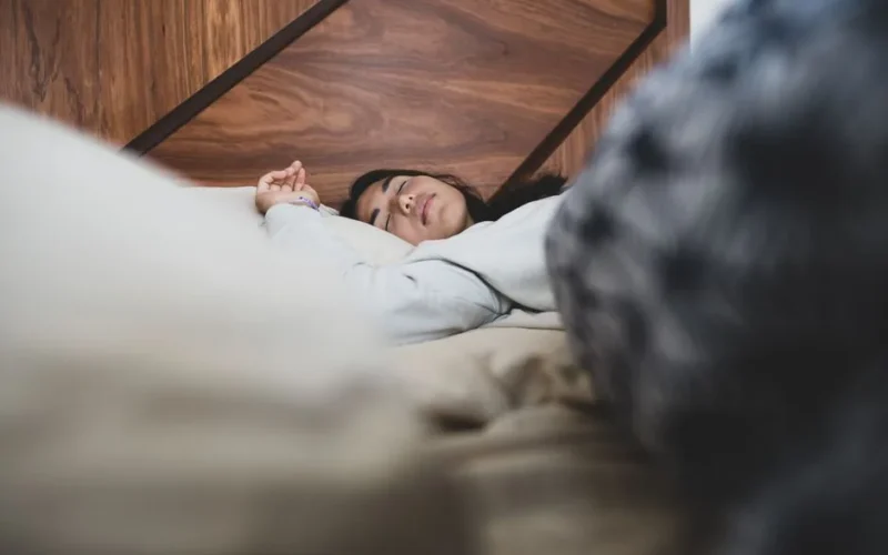 A woman peacefully sleeping on a bed, conveying relaxation and comfort.