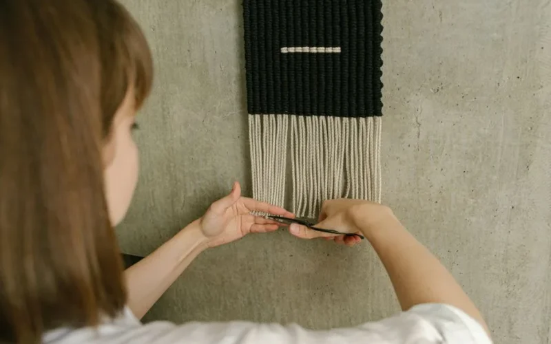 A woman trims fringes on a macramé wall hanging for a stylish home décor touch.