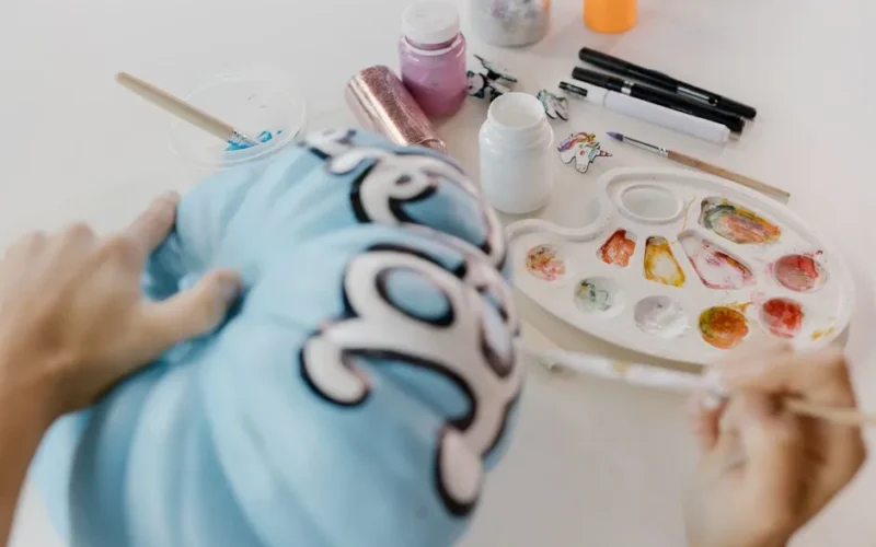 Close-up of a pumpkin being creatively painted for Halloween using colorful paints and a brush.