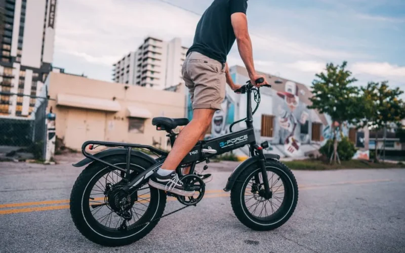 Person riding an electric bike in an urban area with street art and modern buildings.