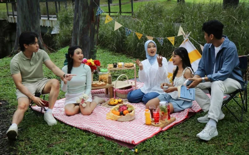 A lively outdoor picnic with friends in a Jakarta park, enjoying food and conversation.