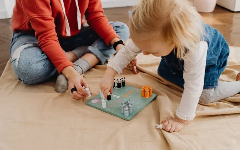 A mother and daughter bonding over a board game indoors, capturing family fun and togetherness.