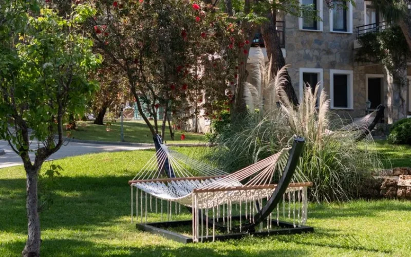 A tranquil garden with a hammock surrounded by lush greenery and blooming trees in Bodrum, Turkey.