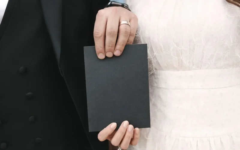 Wedding couple holding a blank card, showcasing their elegant attire.