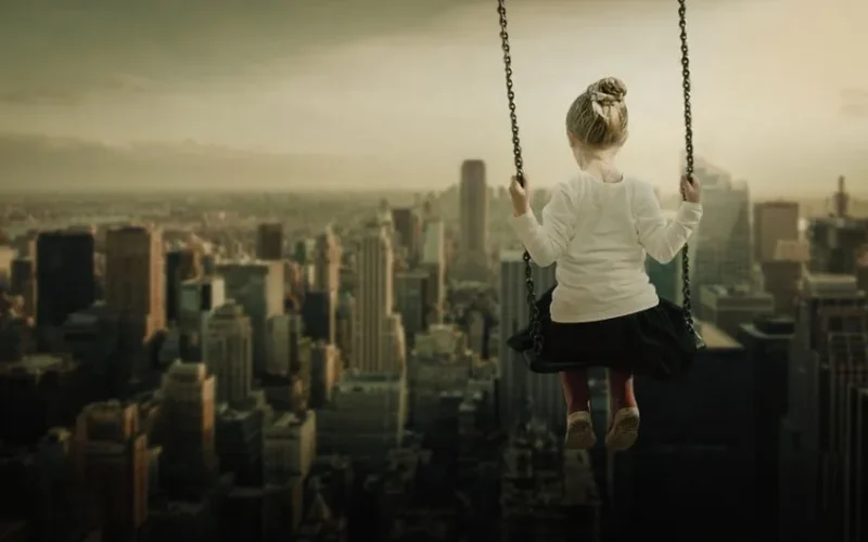 A young girl on a swing set high above a bustling cityscape, capturing imagination and adventure.