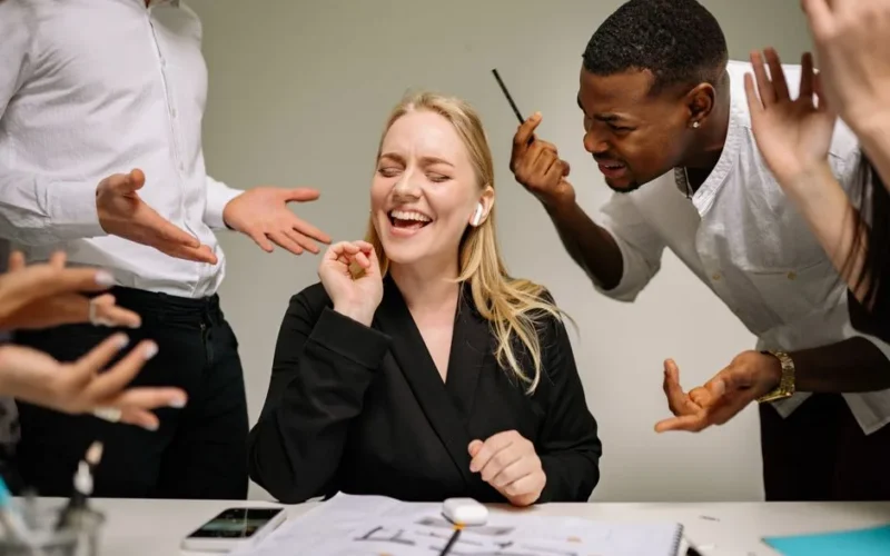 Conceptual image of office conflict with a woman facing workplace pressure surrounded by colleagues.