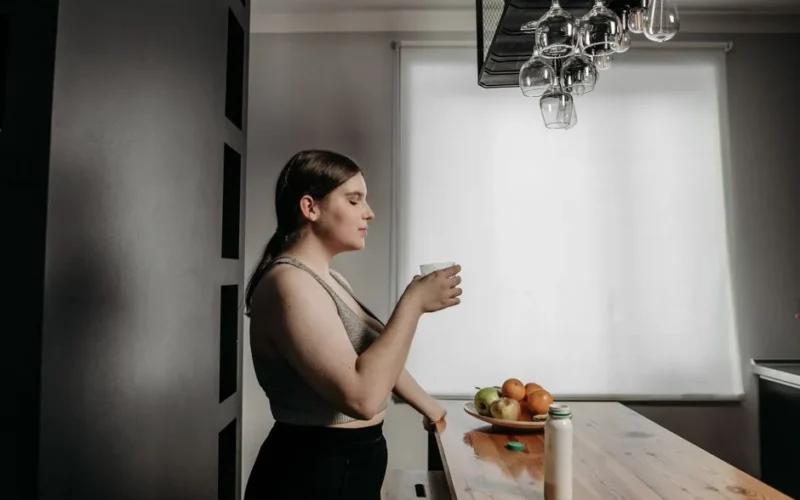 A woman with eyes closed savors a smoothie, embracing a healthy lifestyle in the kitchen.