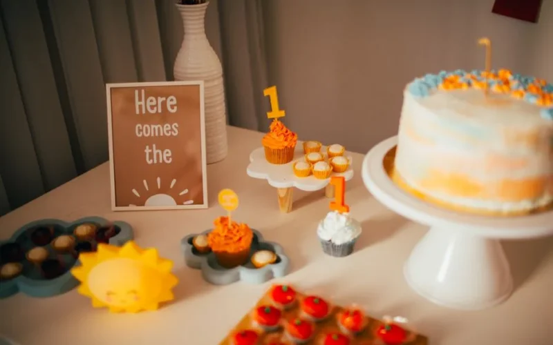 Elegant dessert table setup for a first birthday celebration with cake and cupcakes.