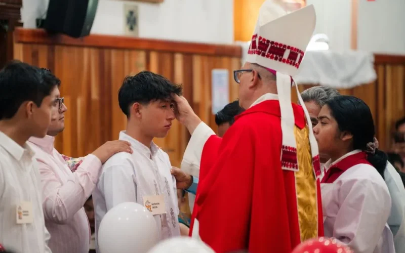 A bishop performs a confirmation ceremony, blessing a young male in a church setting.
